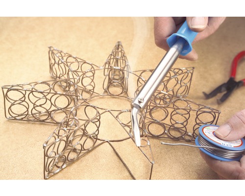 Lötarbeiten an einem metallenen Stern mit Lötkolben und Lötdraht.