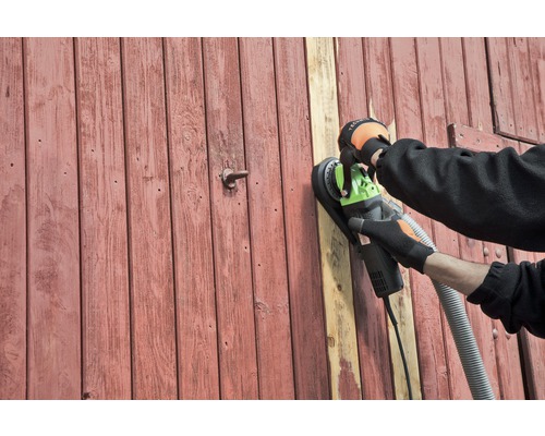 Eine Person schleift eine Holztür mit einem Wandschleifer.