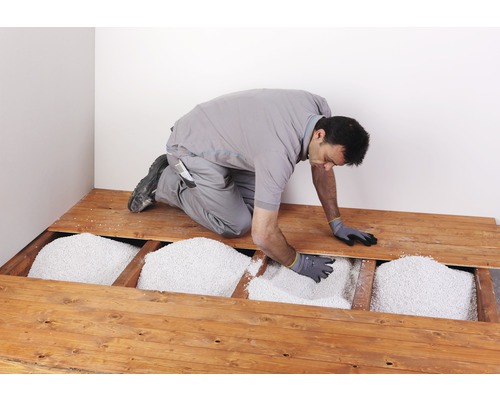 Mann füllt losen Schüttdämmstoff in einen Holzboden ein