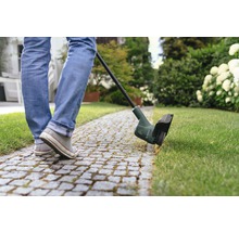 Person verwendet Rasentrimmer im Garten