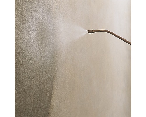 Sprühkopf mit austretender Flüssigkeit vor einer Wand