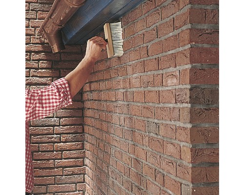 Außenaufnahme einer Person, die eine Fassade mit einer Bürste versiegelt