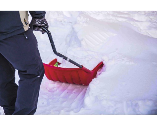 Person schaufelt Schnee mit einer Schneeschaufel