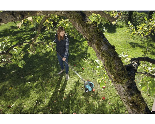 Frau benutzt Obstsammler im Garten unter einem Baum.