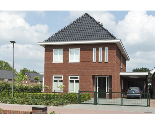 Freistehendes Haus mit Ziegelmauerwerk, dunklem Dach und Garage