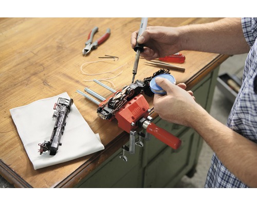 Eine Person repariert eine Modelleisenbahn mit einem Lötkolben und einer Schraubzwinge