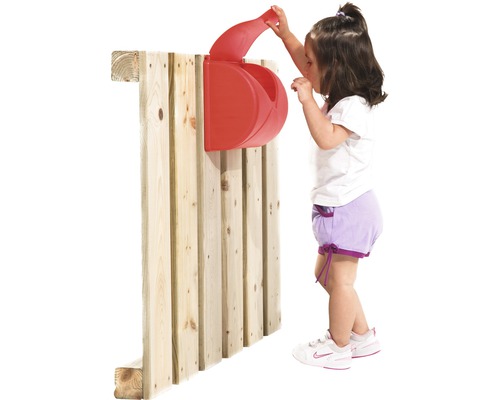 Kind spielt mit rotem Spielzeugbriefkasten an Holzwand