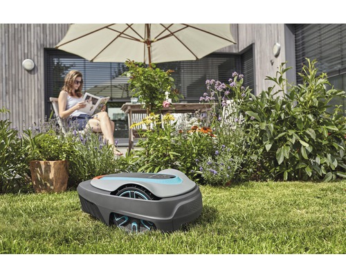 Szene im Garten mit Mähroboter und entspannter Frau im Hintergrund.