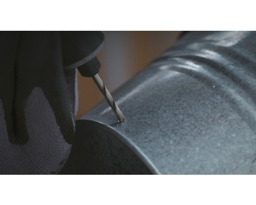 Eine Person bohrt ein Loch in ein verzinktes Rohr.