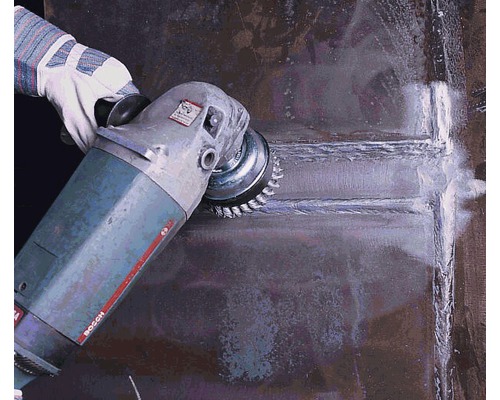 Eine Person verwendet eine Drahtbürste an einer Schleifmaschine zum Reinigen einer Metalloberfläche.