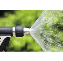 Spritzpistole mit Wasserstrahl vor grünem Hintergrund