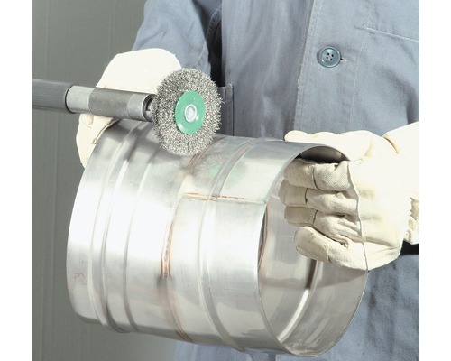 Eine Person reinigt ein Metallrohr mit einer Drahtbürste.