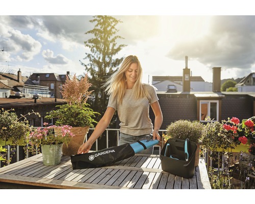 Frau packt Gartengeräte auf einem Holztisch aus einer Tasche.