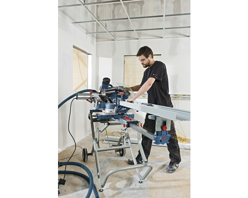 Ein Mann arbeitet mit einer Kappsäge auf einer Baustelle, um ein Werkstück zu schneiden.