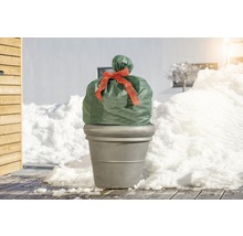 Pflanzkübel mit Winterschutzhaube und Schleife im verschneiten Garten