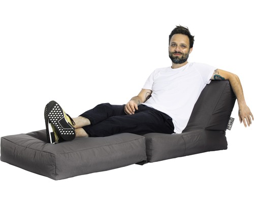 Mann entspannt sich auf einem grauen Sitzsack mit Fußteil