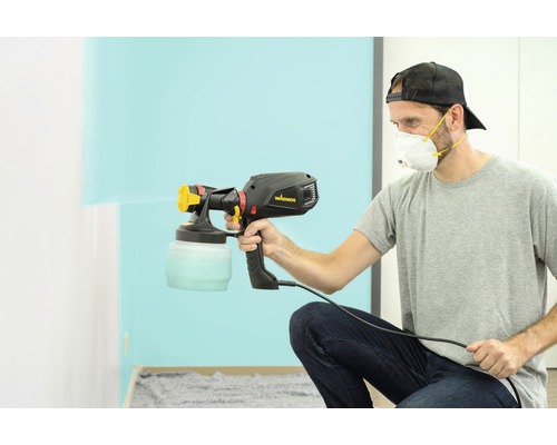 Ein Mann verwendet ein Farbsprühgerät von Wagner, um eine Wand zu streichen.