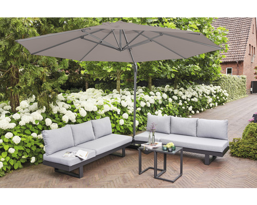 Gartenmöbel-Set mit zwei Sofas, einem Tisch und einem Sonnenschirm im Garten