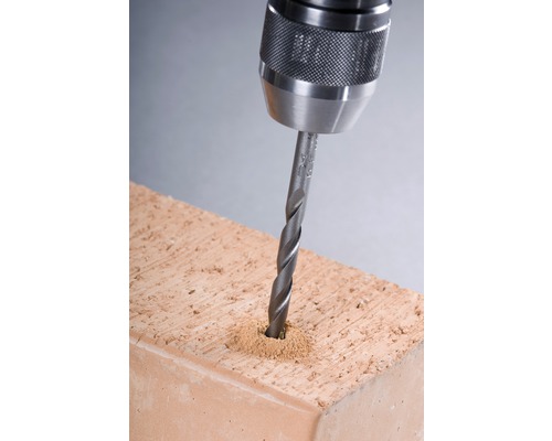 Bohrmaschine bohrt Loch in Ziegelstein