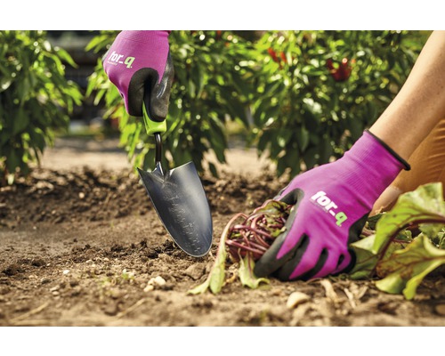 Nahaufnahme einer Person, die mit einer Gartenschaufel und Gartenhandschuhen im Garten arbeitet