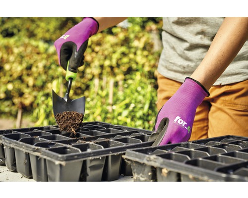 Person befüllt Anzuchtschale mit Erde und Gartenschaufel, geschützt durch Gartenhandschuhe