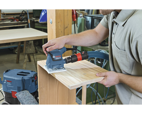 Mann schleift Holz mit einem Bosch Schleifgerät