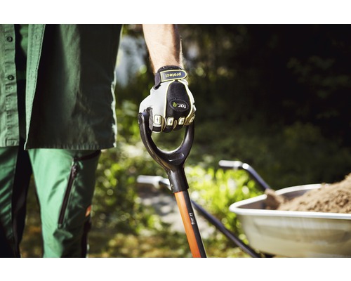 Gärtner hält Spaten mit Handschuhen in der Hand, Schubkarre im Hintergrund