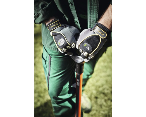 Eine Person in Arbeitskleidung hält mit Gartenhandschuhen einen Spaten.