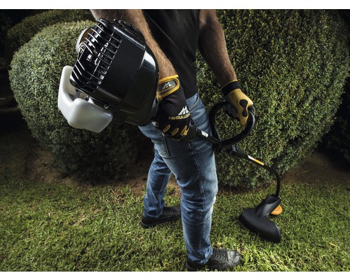 Mann mit Motorsense beim Grasschneiden im Garten