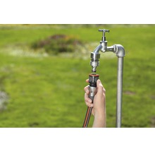 Gartenwasserhahn mit Schlauchanschluss und Gartenschlauch wird verbunden