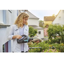 Frau leert einen Gardena Akku-Handsauger über Blumen aus