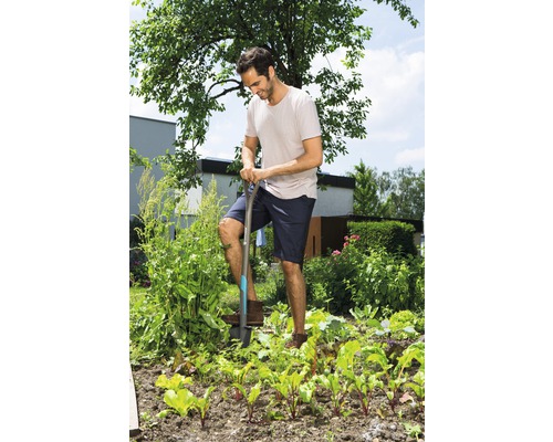 Ein Mann gräbt mit einem Spaten ein Gemüsebeet im Garten um.
