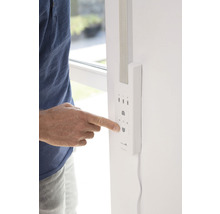 Person bedient eine Rollladensteuerung an der Wand