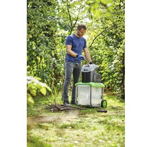 Ein Mann benutzt einen Gartenhäcksler im Garten.