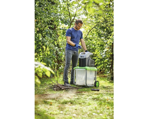 Ein Mann benutzt einen Gartenhäcksler im Garten.