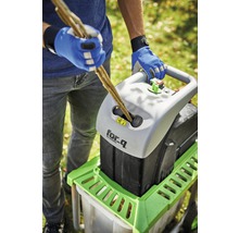 Eine Person führt Äste in einen Häcksler der Marke for_q ein.