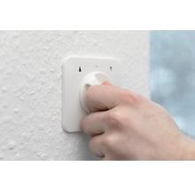 Hand bedient einen weißen Smart Home Drehregler an einer Wand