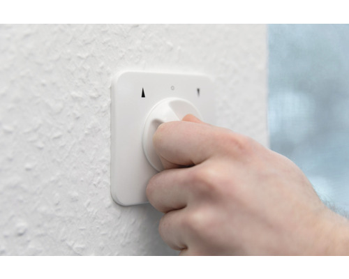 Hand bedient einen weißen Smart Home Drehregler an einer Wand