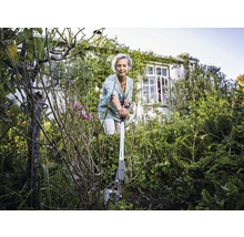 Frau benutzt eine Unkrautwurzelzange im Garten.