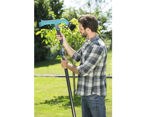 Mann mit einer Teleskopstiel-Gartenbürste im Garten.