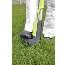 Person benutzt einen Unkrautstecher im Garten