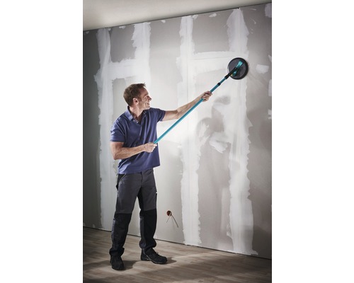 Ein Mann schleift eine Wand mit einem Langhalsschleifer