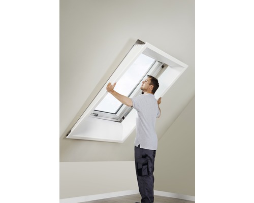 Mann montiert Dachfenster im Dachgeschoss.