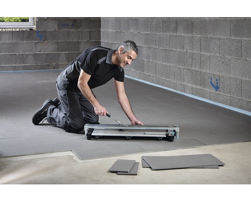 Ein Mann benutzt einen Laminatschneider zur Laminatverlegung.