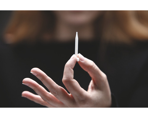 Eine Hand hält einen Injektor.