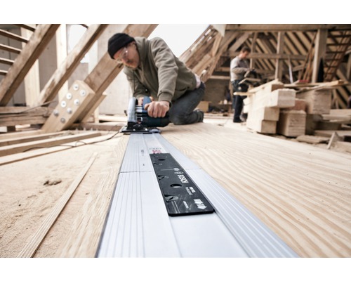 Handwerker arbeitet mit einer Handkreissäge und Führungsschiene auf einer Baustelle