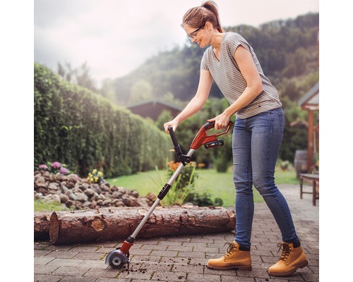 Frau verwendet einen Kantenschneider auf einer Terrasse im Garten.