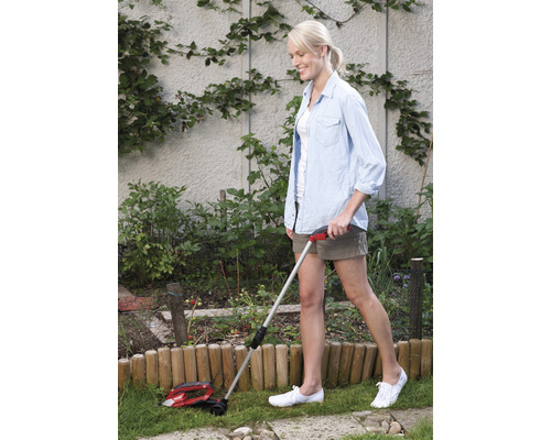 Frau benutzt eine Rasenkantenschere im Garten.