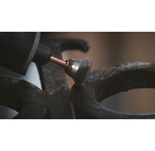 Eine Schleifmaschine mit Drahtbürstenaufsatz schleift eine Metalloberfläche.