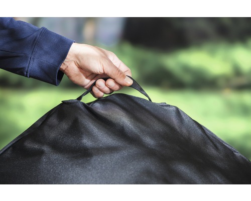 Person hält Abdeckhaube für Gartenmöbel am Tragegriff